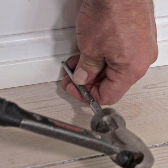 Liste mellem fodpanel og gulv: SlåLista jalkalistan ja lattian väliin: Upota naulat tuurnalla dykkerne ind med en dyknagle Lista jalkalistan ja lattian väliin: Upota naulat tuurnalla